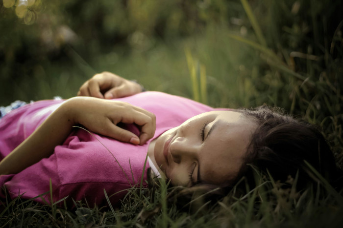 A woman sleeping in a field of grass